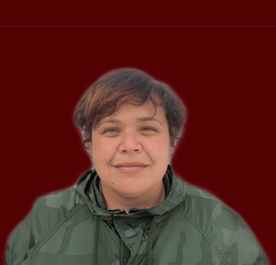 Fotografía tipo retrato de una persona con chaqueta verde militar, posando sobre un fondo rojo oscuro liso, ideal para uso profesional, institucional o ficha de equipo en sitio web.